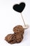 Tastefuls cookie lying on a clear white surface next to Black heart figurine standing on small column.
