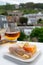 Tastes of Normandy, homemade baked crepe pancake with goat cheese and salmon and glass of apple cider drink with houses of Etretat