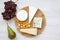 Tasting cheese with fruits on a white wooden background. Food for wine, top view. Flat lay.