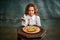 Tasting pizza. Portrait of little charming girl with curly hair in vintage blouse eating pizza over dark green