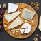 Tasting various type of cheeses on round wooden board with fruits, walnuts and pretzels. Food for wine. Top view, overhead