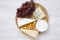 Tasting various types of cheese with grapes on a round wooden board. Food for wine, top view. Flat lay.