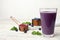 Tasty acai drink in glass, berries and powder on wooden table
