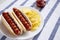 Tasty American Hot Dog with Potato Chips on a white plate, side view. Space for text