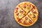 Tasty Americana Pizza with french fries, wurstel, cheese, tomato sauce and herbs close-up on a wooden board. Horizontal top view