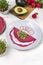 Tasty appetizing beetroot pancakes served on plate with avocado, sprouts and pink radish, white wooden table