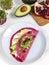 Tasty appetizing beetroot pancakes served on plate with avocado, sprouts and pink radish, white wooden table