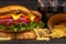 Tasty appetizing burgers on wooden board, glasses with soda and french potato on black background. Fast food concept. Restaurant