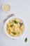 Tasty appetizing classic italian penne pasta with parmesan cheese and basil in white plate on plate on on stone table. Traditional