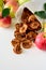 Tasty apple chips wrapped in paper on white wooden background