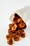 Tasty apple chips wrapped in paper on white wooden background