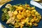 Tasty baked yellow carrot with broccoli, cauliflowers and pea sprouts on blue plate, closeup