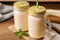 Tasty banana smoothie and mint on wooden table, closeup