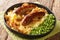 Tasty Bangers and Mash made of sausages served with mashed potatoes, green peas and onion gravy close-up in a plate. Horizontal