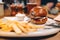 Tasty beef burger with lettuce and mayonnaise served on white plate with french fries. modern dinner with burger and fries