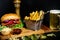 Tasty beef burger served with fries and lettuce on wooden board at local pub