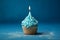 Tasty birthday cupcake with a candle on a blue background. Mini cake. Ai generative