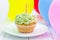 Tasty birthday cupcake with candle, colorful balloons on background