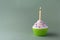Tasty birthday cupcake with candle, on green background, with free space