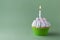 Tasty birthday cupcake with candle, on green background, with free space