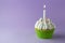 Tasty birthday cupcake with candle, on purple background, with free space