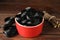 Tasty black candies and dried sticks of liquorice root on wooden table, closeup