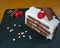 Tasty Black forest slice decorated with cherries and decorative and colorful sugar sprinkles on a black slate board