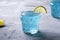 Tasty blue colored cocktail drink with basil chia seeds and citrus lime slice in two glass, healthy summer beverage