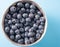 Tasty blueberries in silver bowl on a blue panited wooden table.