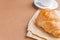 Tasty breackfast. French croissant served on white plate and cup of black coffee or espresso on brown background. Copy space