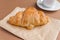 Tasty breackfast. French croissant served on white plate and cup of black coffee or espresso on brown background. Copy space