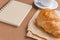 Tasty breackfast. French croissant served on white plate and cup of black coffee or espresso on brown background. Copy space