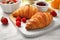 Tasty breakfast with croissants served on white wooden table