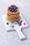 Tasty breakfast. Homemade pancakes with fresh cranberry, blueberry and spring flower on white wooden cutting board