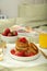 Tasty breakfast served in bedroom. Cottage cheese pancakes with strawberries and honey on white tray