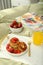 Tasty breakfast served in bedroom. Cottage cheese pancakes with strawberries and honey on white tray