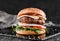 Tasty burger with cheese brie, blue cheese, mozzarella, tomatoes and arugula on slate black background, close up