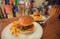 Tasty burger with french fries and sauces served at the table of a crowded fast-food cafe. Dinner, breakfast or lunch