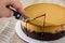 Tasty cake with condensed milk on a wooden background. A hand cuts a piece of cake with a knife.
