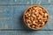 Tasty cashew nuts in bowl on color wooden table, top view