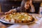 Tasty cheese pizza on vintage-looking table with little girl as background