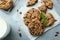 Tasty chocolate chip cookies, glass of milk and mint leaves on light grey table, flat lay