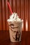 A tasty Chocolate Milkshake with chocolate syrup drizzel and whip cream.