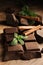 Tasty chocolate pieces, cinnamon sticks and mint on wooden table, closeup