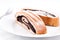 Tasty cocoa roll cakes sprinkled with sugar on a plate with a fork, isolated on white background.