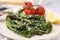 Tasty cooked broccolini with cheese, tomatoes and lemon on plate, closeup