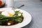 Tasty cooked broccolini with poached egg, almonds and sauce on grey table, closeup. Space for text