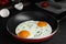 Tasty cooked eggs with herbs in frying pan on black table