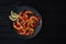 Tasty cooked fried shrimp with chilli and lemon on a black wooden background. Healthy seafood. Copy space.