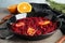 Tasty cranberry sauce with citrus fruit slices in pan on table